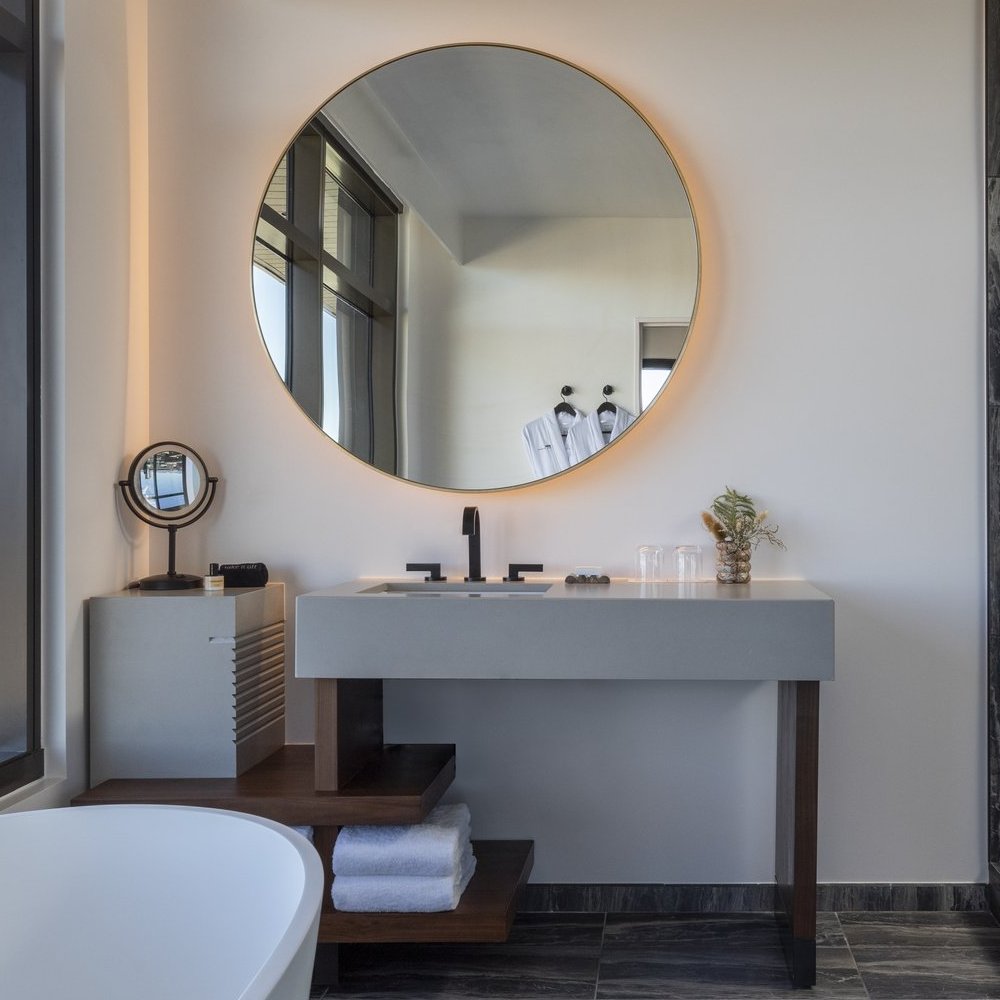 Round backlit mirror above a floating grey vanity in a guest bathroom at Thompson Denver